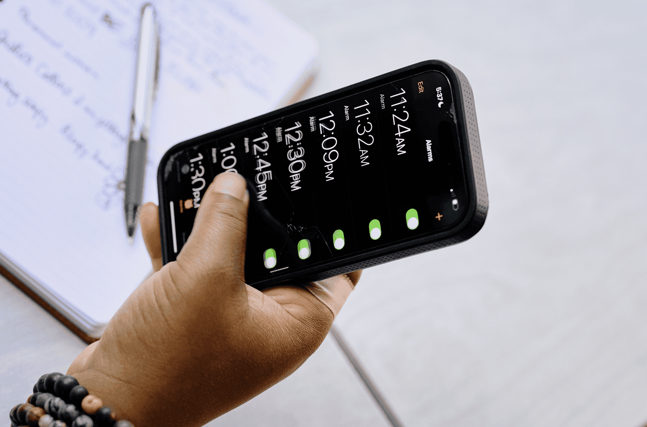 A person holding an iPhone with multiple alarms set