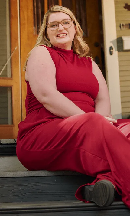 Woman with narcolepsy type 1 sitting on the steps of her front porch and smiling