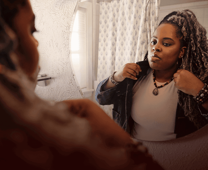 Woman with narcolepsy type 1 fixing her collar in a bathroom mirror