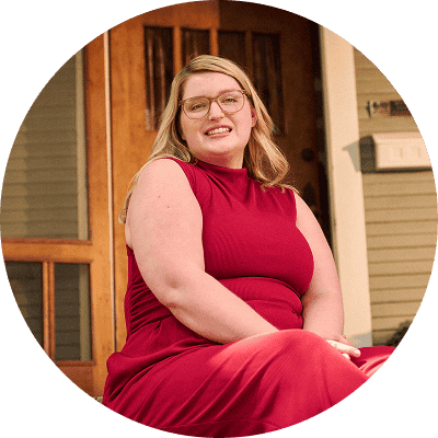Woman with narcolepsy type 1 sitting on the steps of her front porch and smiling