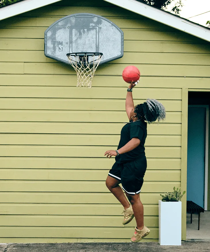 Woman with narcolepsy type 1 jumping and one-hand shooting a basketball into a hoop