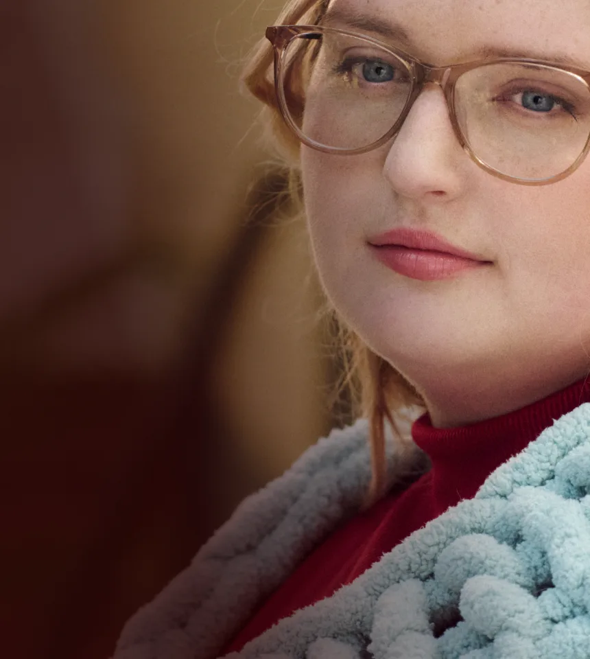 Woman with narcolepsy type 1 posing outdoors while wrapped in a knitted blanket